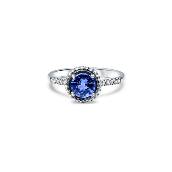 Bague de fiançailles ornée d'un saphir bleu de culture de 0.80ct. et entourée d'un halo et serti sur le partout d'un délicat pavé de diamants de culture.